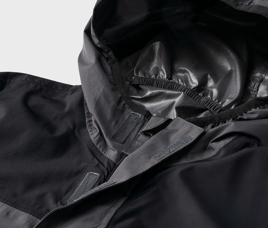Nahaufnahme einer schwarzen Jacke mit Kapuze, die mit Klettverschluss befestigt wird.