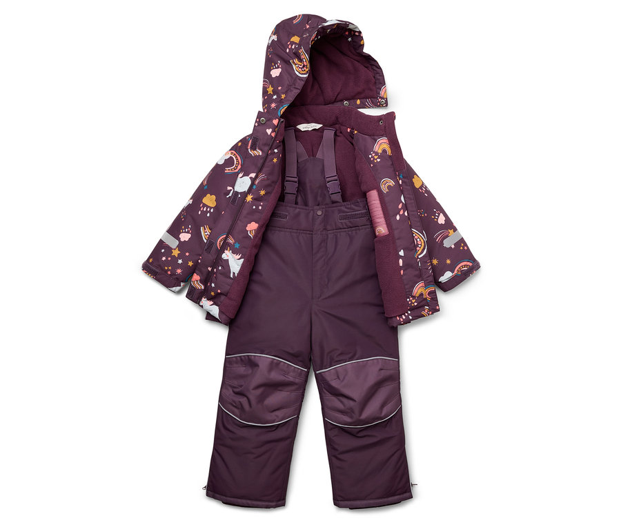 Lila Kinder-Schneeanzug und Jacke mit Einhorn-, Stern- und Regenbogenmuster liegen auf dem Boden.