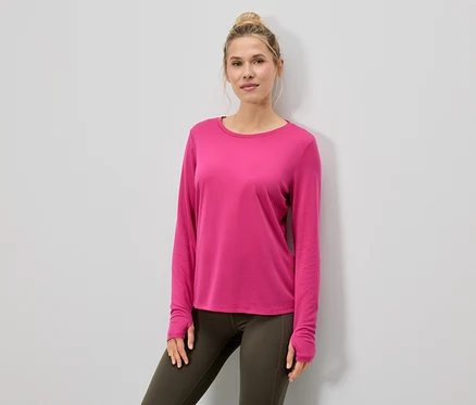 Frau trägt ein pinkes Langarmshirt und Leggings.