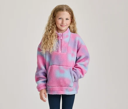 Lächelndes Mädchen mit blonden Locken trägt einen pink-lila-blauen Tie-Dye-Fleece-Pullover mit Reißverschluss und Bauchtasche.