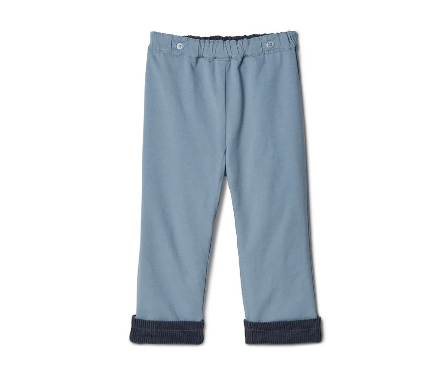 Hellblaue Hose mit elastischem Bund und zwei Knöpfen. Die Hosenbeine sind hochgekrempelt und zeigen ein dunkelblaues Rippfutter.