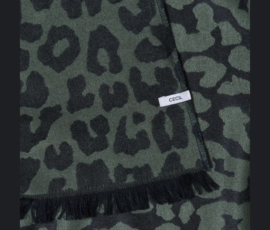 Dunkelgrüner CECIL Poncho mit schwarzem Leopardenmuster, Fransen und weißem „CECIL“-Etikett.