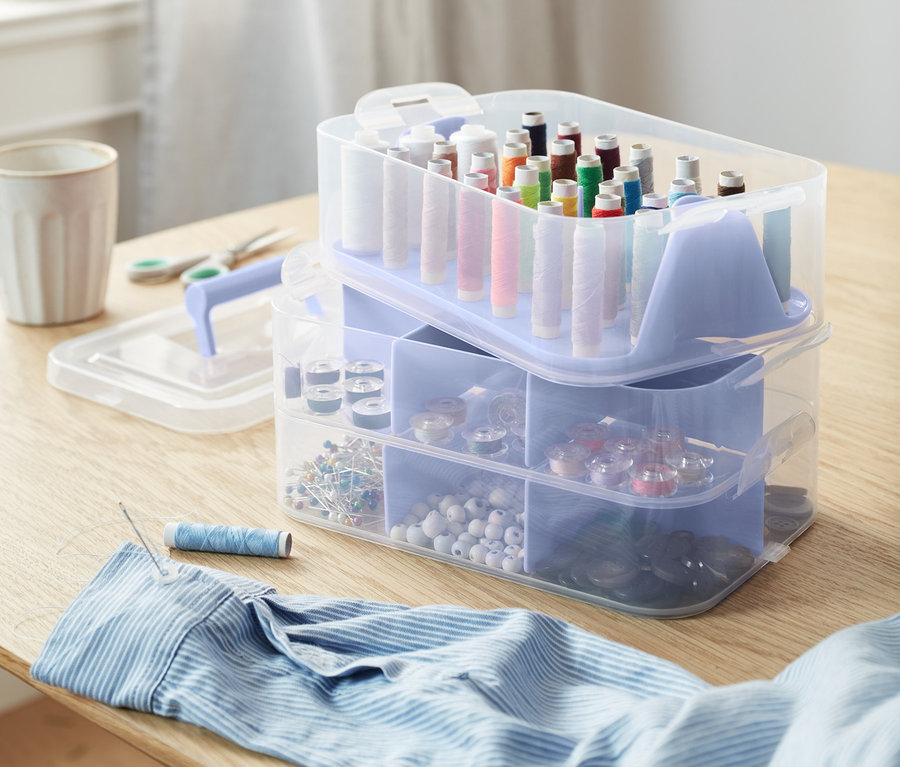 Organizerboxen mit Nähgarn, Knöpfen und Nähzubehör auf einem Tisch.