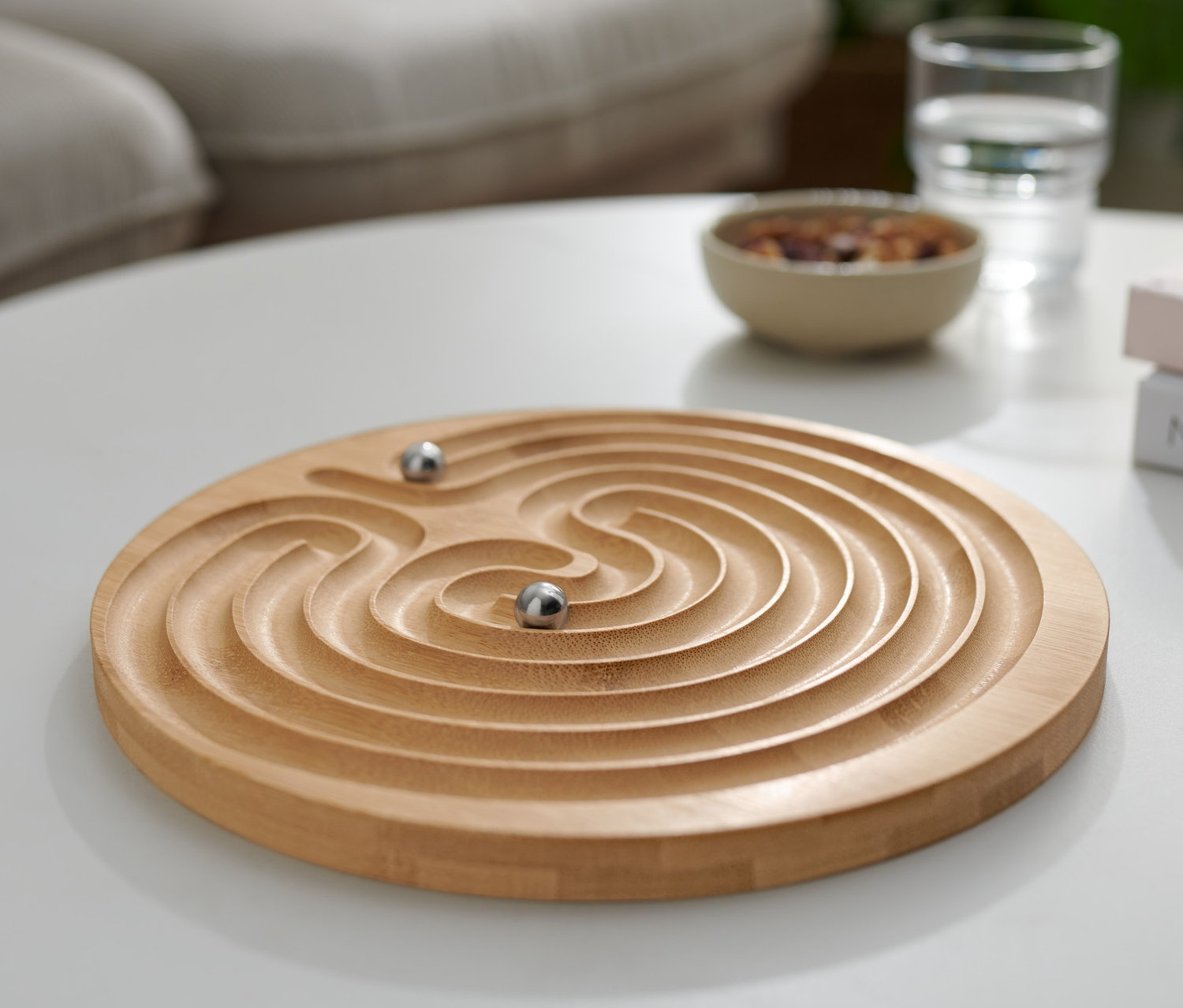 Auf einem weißen Tisch liegt ein Geduldsspiel »Labyrinth« mit zwei Kugeln.