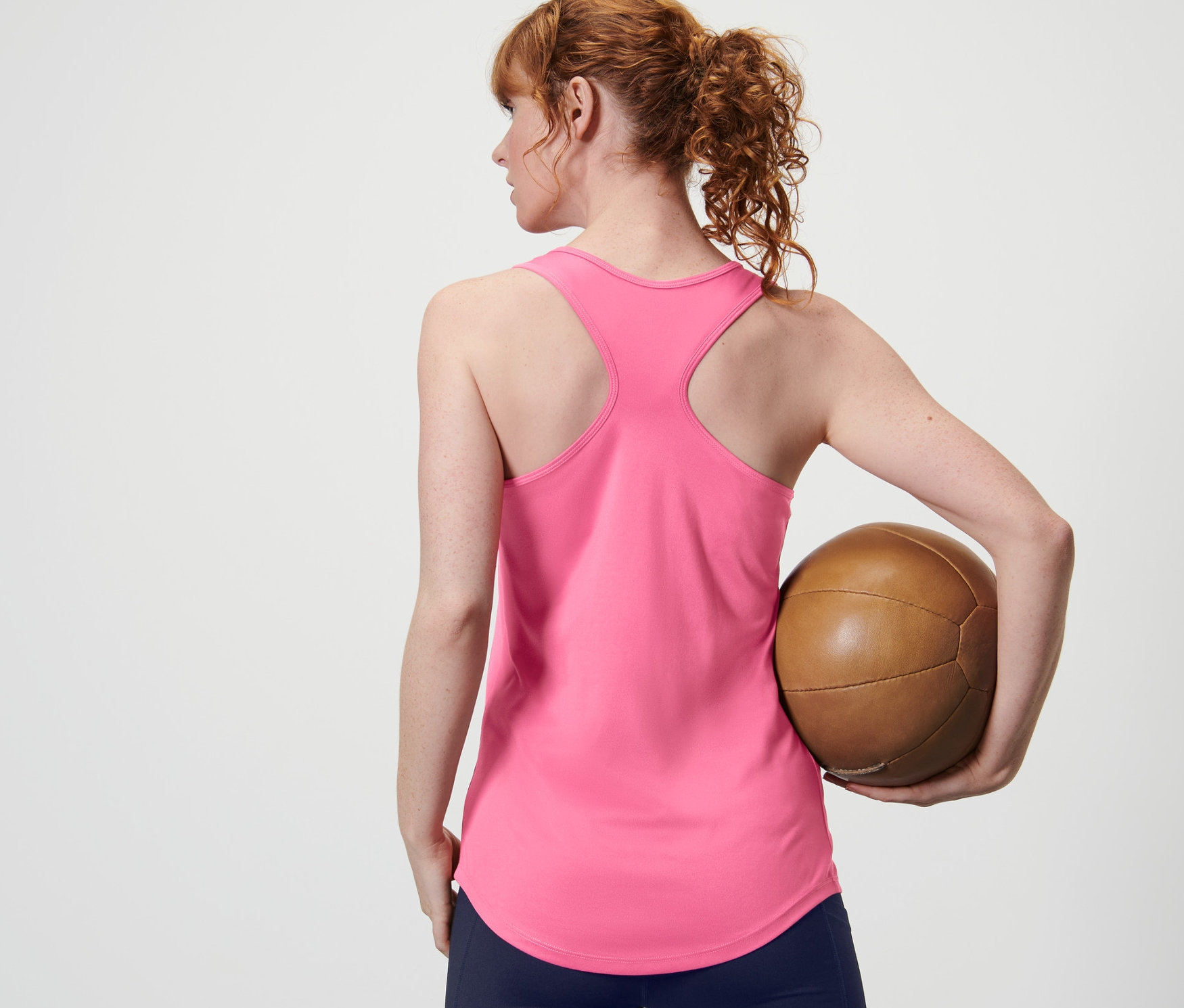 Frau hält von hinten einen braunen Ball und trägt ein pinkes Funktionstop von 2er Set.