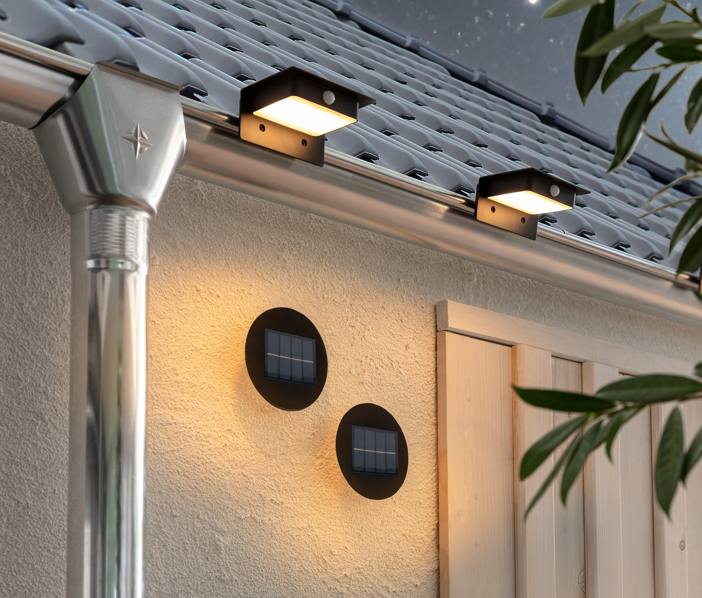 Zwei Solar-Wand-und-Stufenlichter und drei Solar-Dachrinnenleuchten sind an der Wand und der Dachrinne des Hauses befestigt.