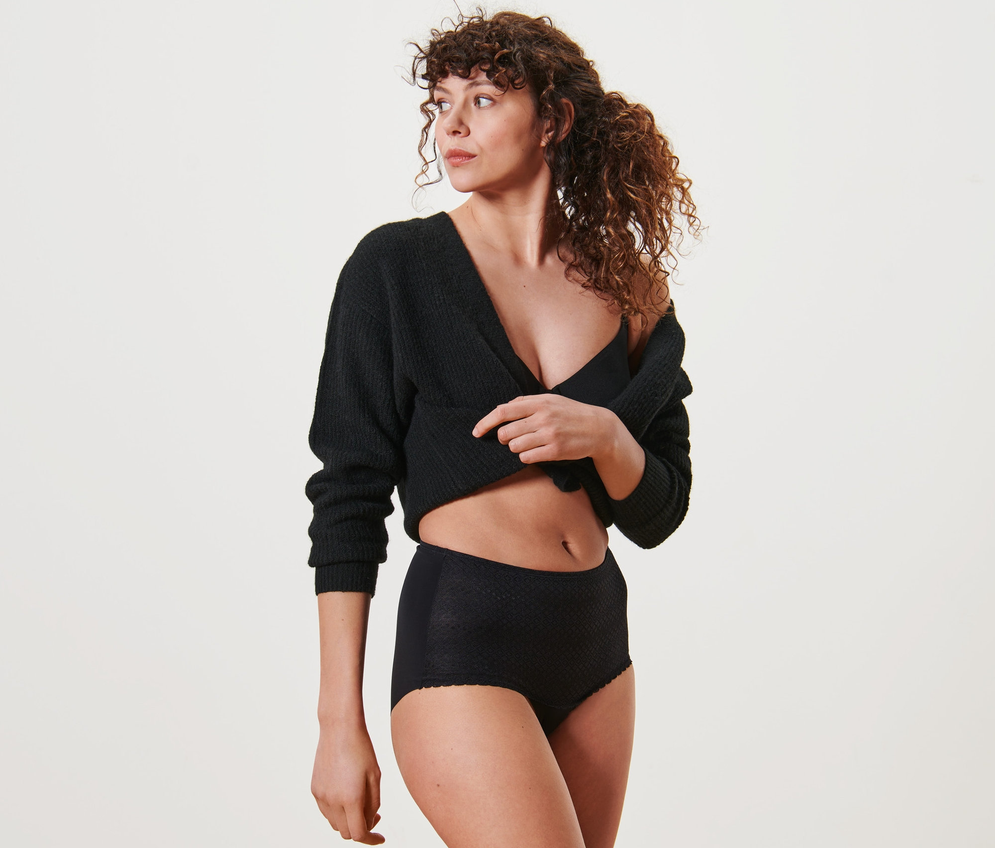 Frau posiert in schwarzem Cardigan und Highwaist-Panty.