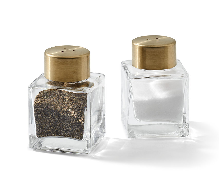 Zwei gläserne Salz- und Pfefferstreuer mit goldenen Deckeln.