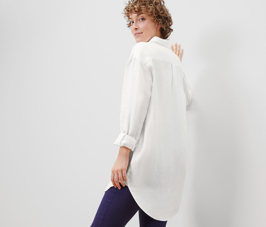 Frau blickt über die Schulter und posiert in Leinenbluse.