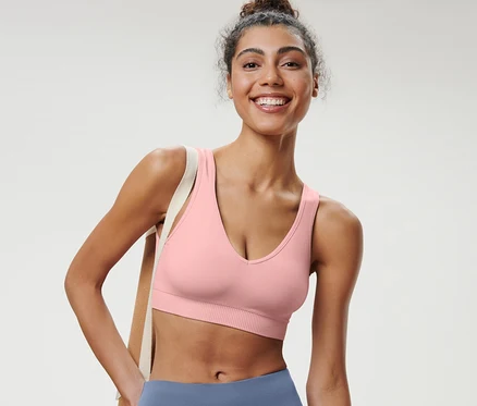 Eine lächelnde Frau trägt ein roséfarbenes Seamless-Sport-Bustier.