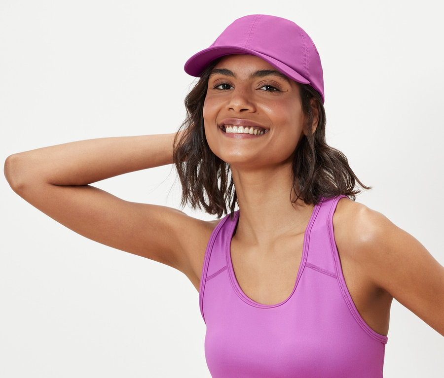 Frau posiert in Sport-BH und Sport-Kappe.