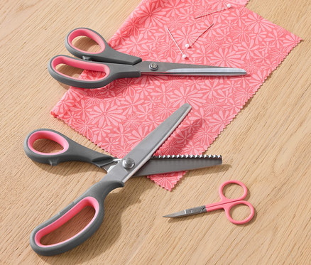 Ein Stoffscheren-Set liegt auf einem Stück Stoff mit Blumenmuster.