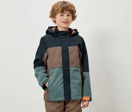 Ein Junge trägt eine farbenfrohe Kinder-Allwetterjacke.