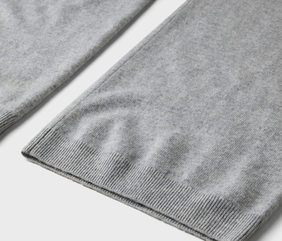 Detailaufnahme eines grauen Strickstoffes mit geripptem Saum.