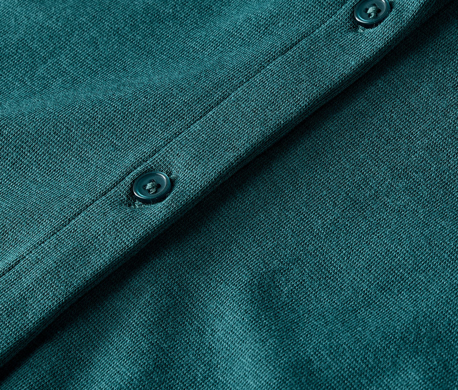 Detailaufnahme eines grünen Strickcardigans mit Knöpfen.