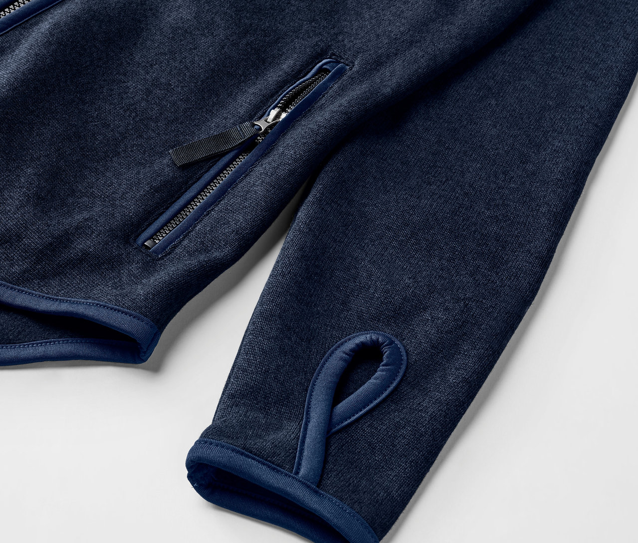 Detail einer Strickfleece-Jacke, navy, mit Daumenloch und Reißverschlusstasche.