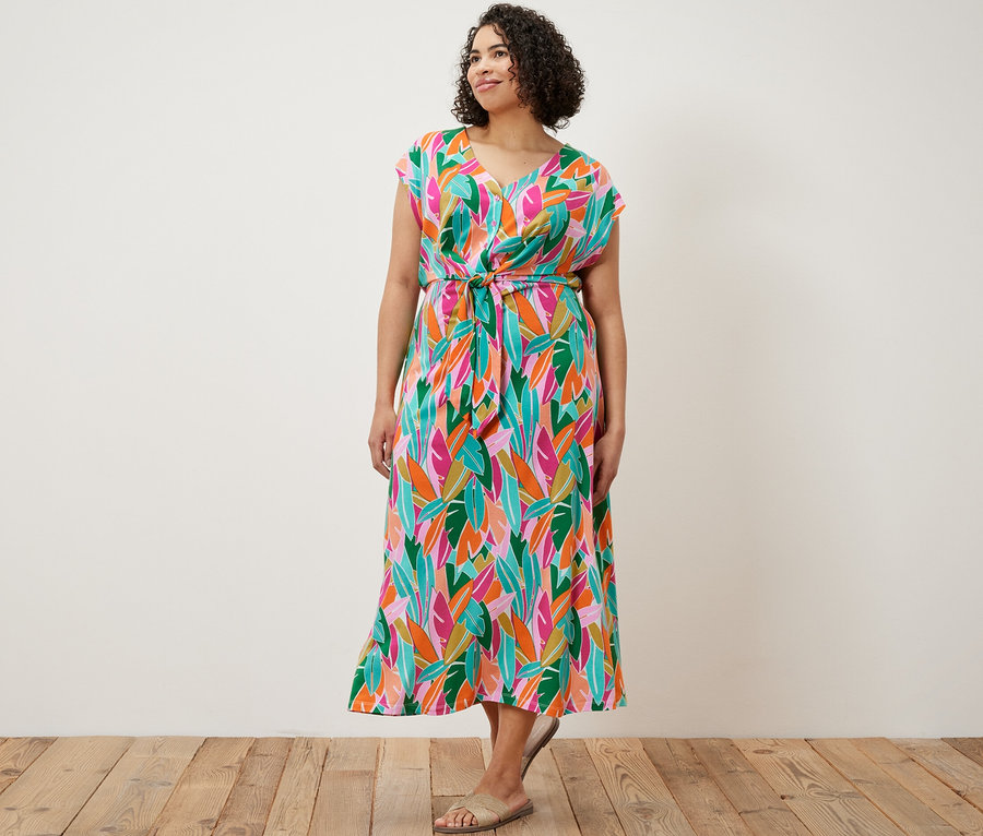 Frau steht und trägt ein Jerseykleid mit Knoten.