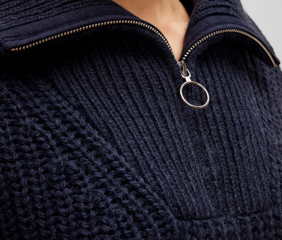 Detailaufnahme eines dunkelblauen Strickpullovers mit Reißverschluss.