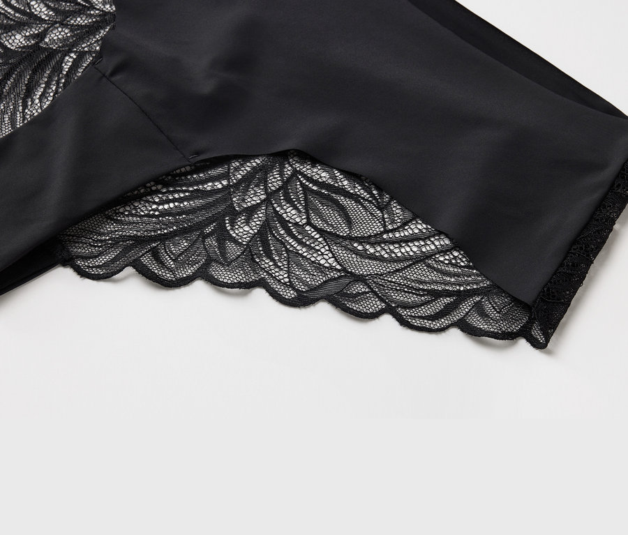 Detailansicht eines schwarzen Stoffes mit floraler Spitze am Saum.