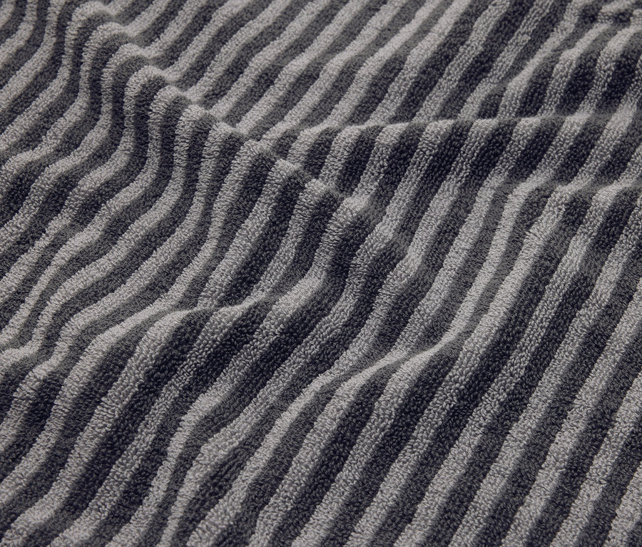 Nahaufnahme eines gestreiften, grauen Handtuchs mit Falten.