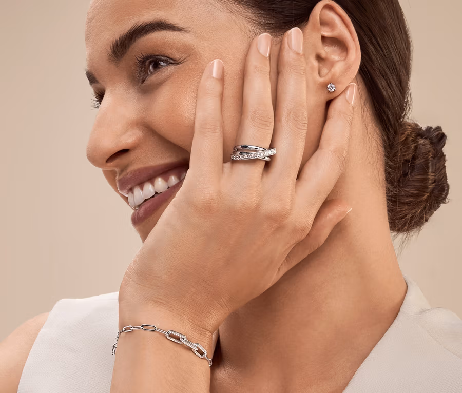 Frau mit Silberring und Armband lächelt und schaut nach links.