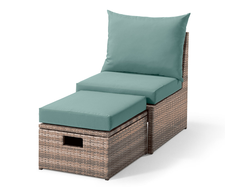 Ein Lounge-Sessel mit Fußteil aus Polyrattan mit türkisfarbenen Kissen.