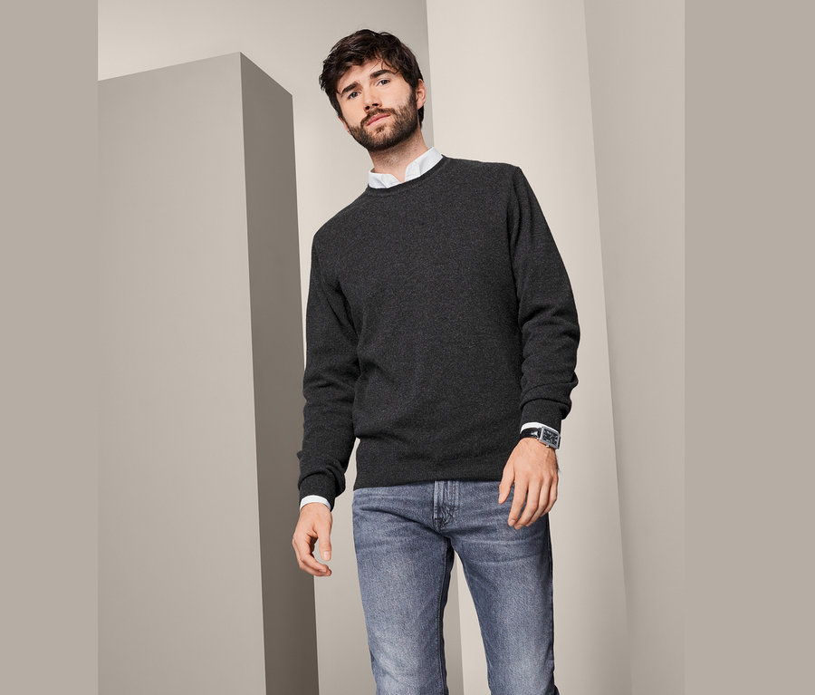 Mann trägt einen Cashmere-Pullover mit Rundhalsausschnitt, Jeans und eine Uhr.