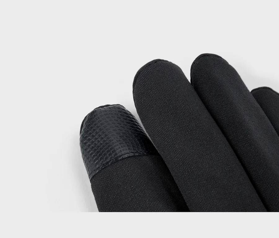 Nahaufnahme von schwarzen Softshell-Handschuhen, die eine texturierte Fingerspitze und glatten Stoff zeigen.