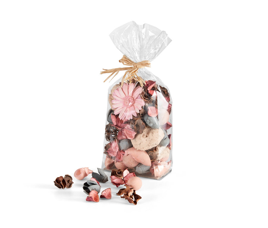 Eine Packung Duft-Potpourri mit rosa Blüten und Zapfen, einige daneben verstreut.