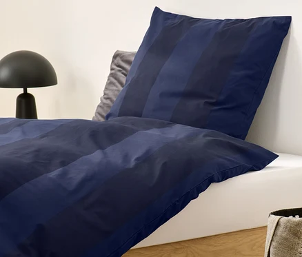 Blau gestreifte Edelflanell-Bettwäsche in Normalgröße auf einem Bett.