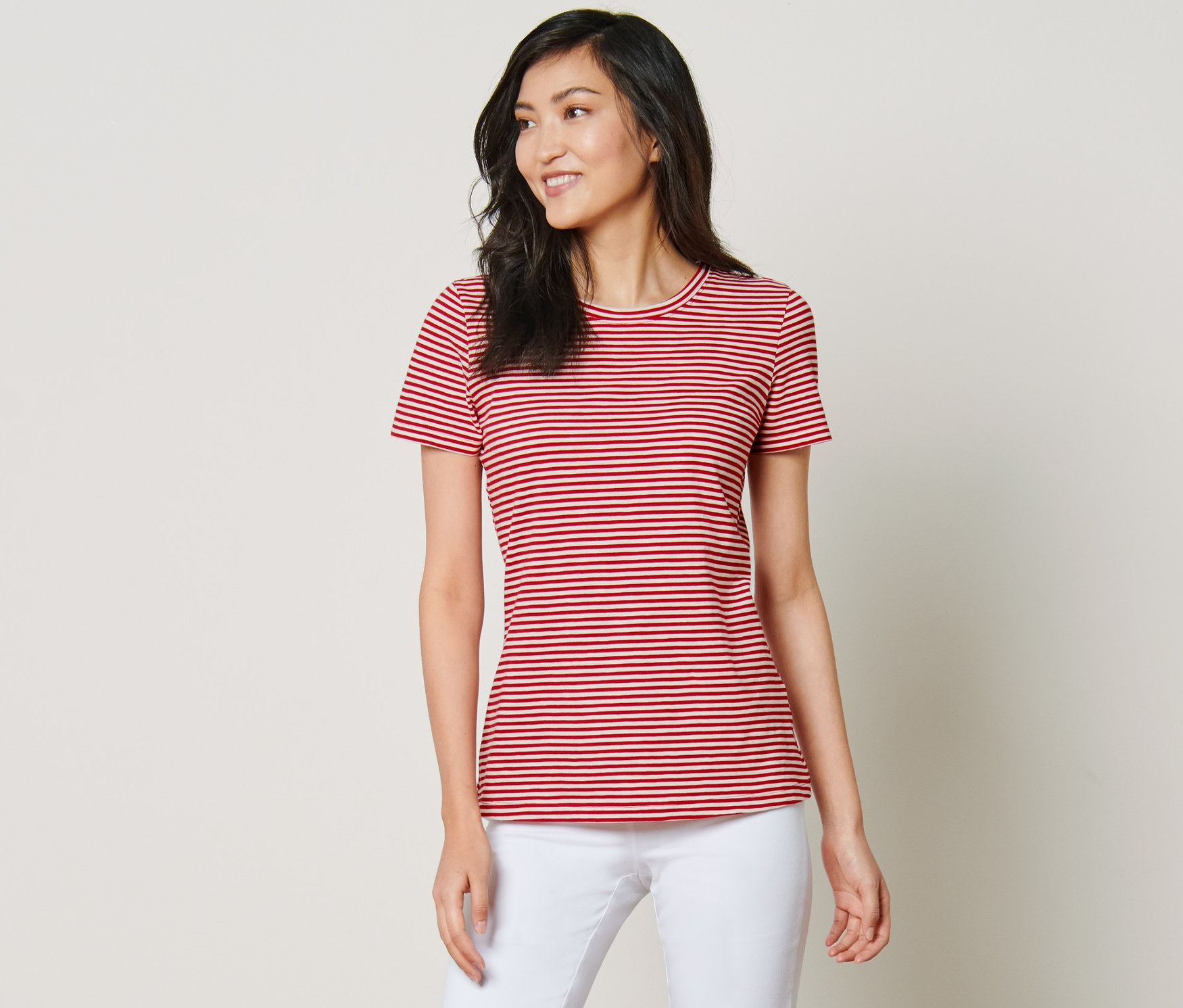 Frau posiert in gestreiftem T-Shirt und weißen Hosen.