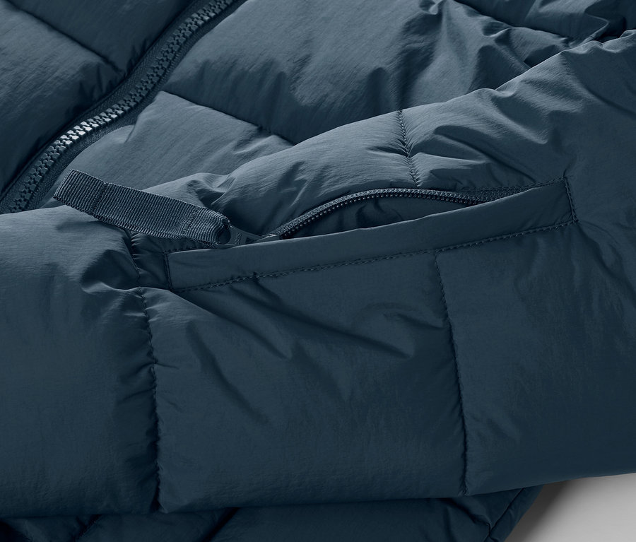 Detailansicht einer dunkelblauen Ski-Steppjacke mit Reißverschluss und Tasche.
