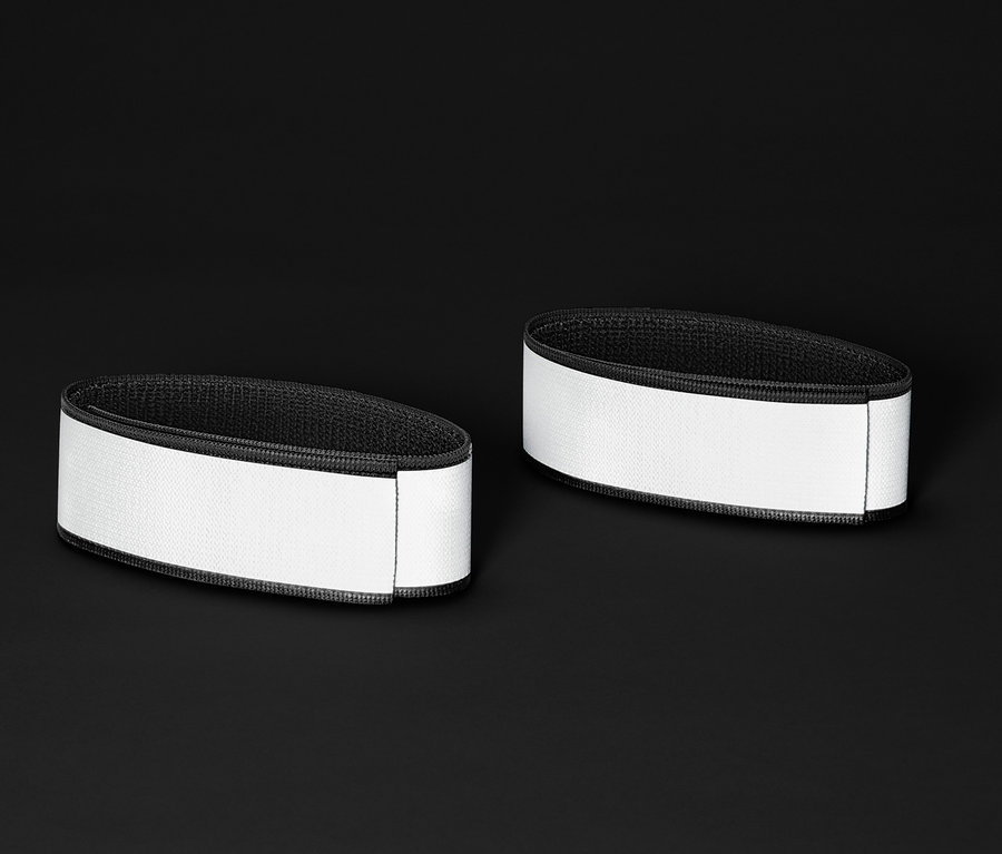 Zwei Reflektor-Hosenbänder liegen auf einem schwarzen Hintergrund.