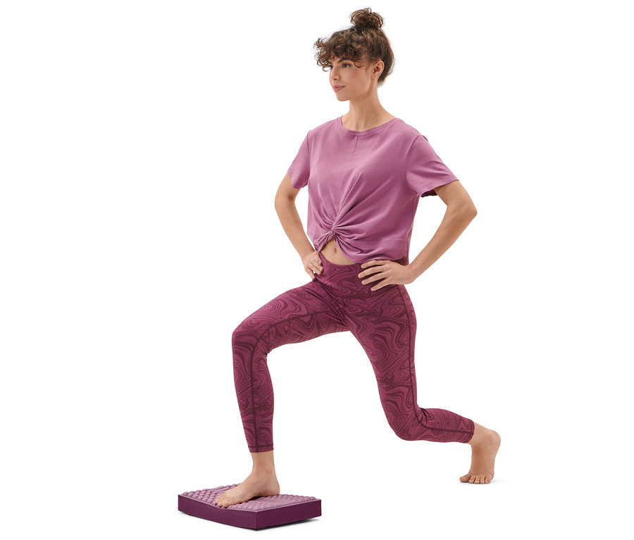 Frau macht einen Ausfallschritt auf einem Balance- und Massage-Pad.