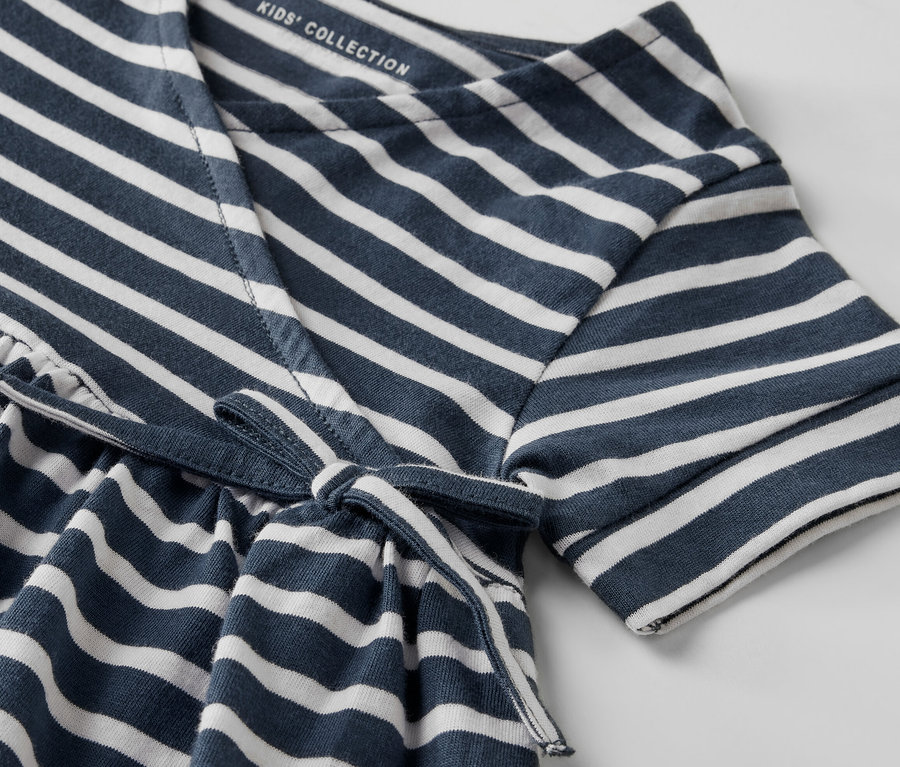 Detailansicht eines Kinder-Jerseykleids mit blauen und weißen Streifen und einer Taillenschnürung.