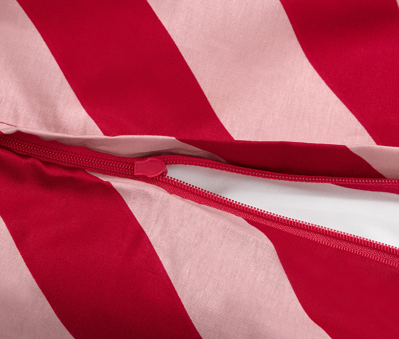 Detailaufnahme eines rot-weiß gestreiften Bettbezugs mit Reißverschluss.
