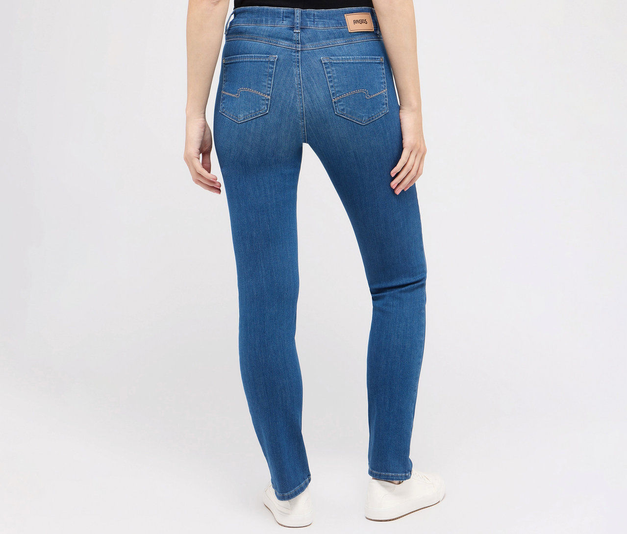 Rückansicht einer Frau, die Angels Jeans »Cici« Slim Fit, mid blue und weiße Schuhe trägt.