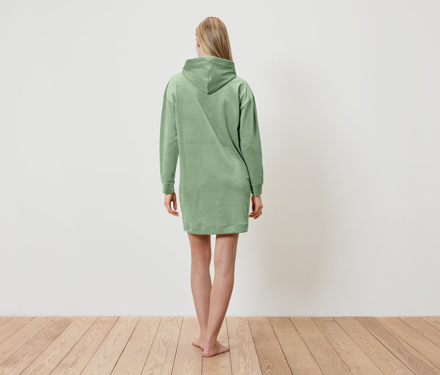 Frau steht mit dem Rücken zur Kamera und trägt ein grünes Hoodie-Kleid.
