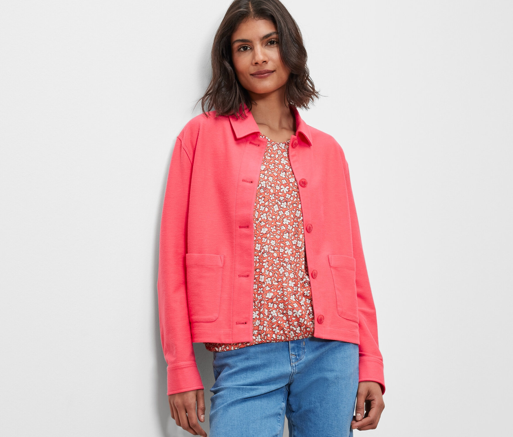 Frau trägt eine pinke Jerseyjacke und Jeans.