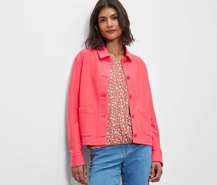 Frau trägt eine pinke Jerseyjacke und Jeans.