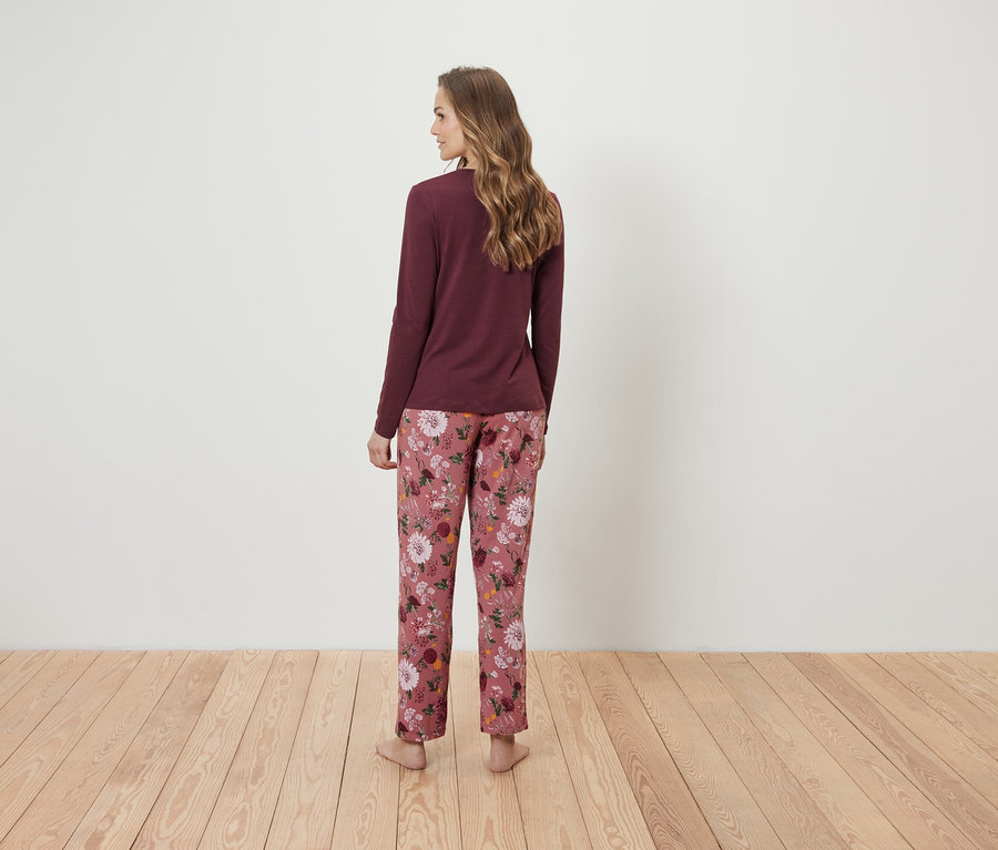 Frau von hinten trägt ein weinrotes Langarmshirt und eine rosafarbene Blumenpyjamahose.