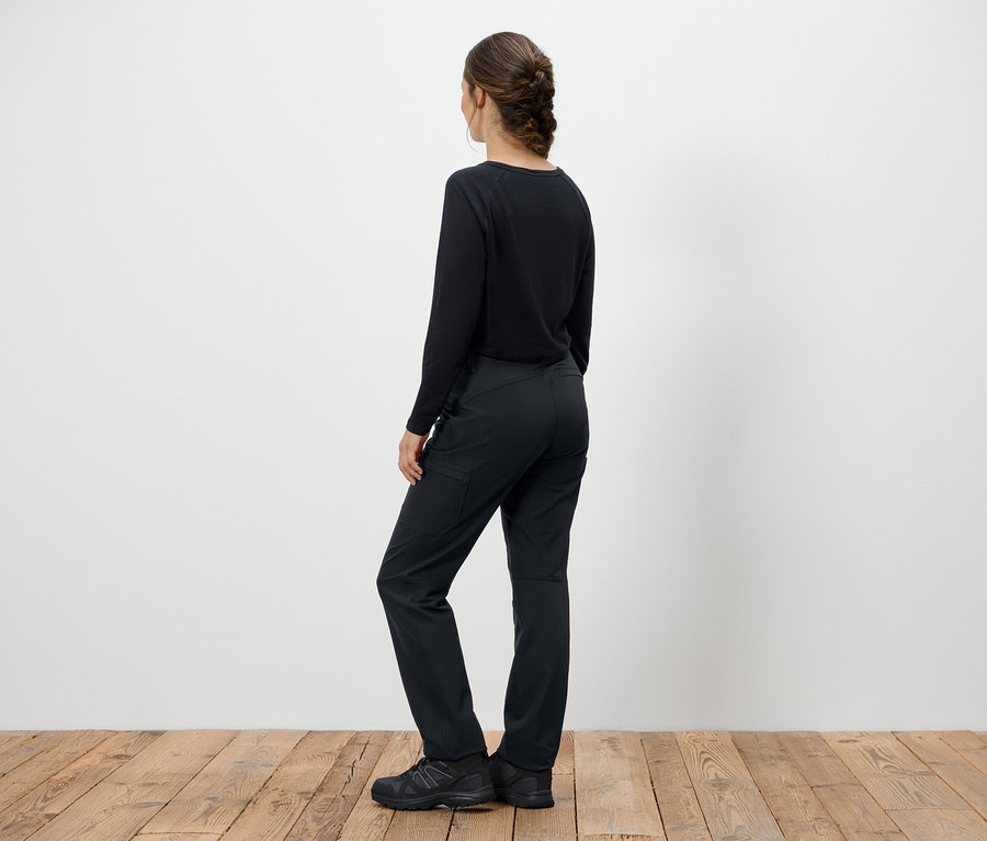 Frau in schwarzem Pullover und Hose steht mit dem Rücken zur Kamera.