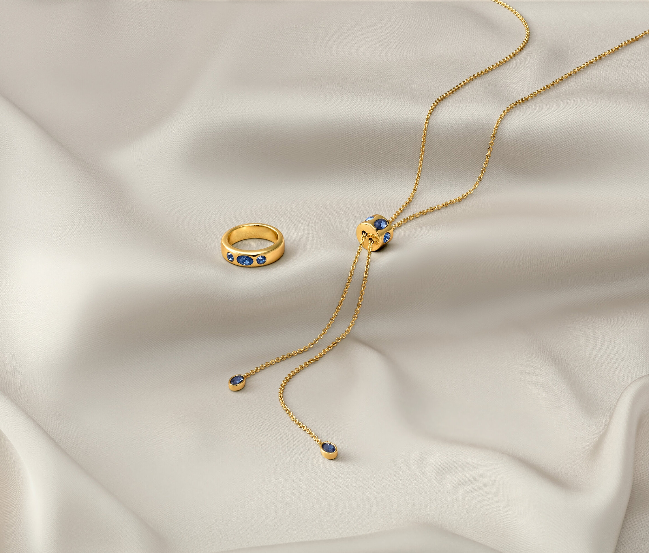 Auf einem weißen Tuch liegen eine goldene Kette »Iconic« und ein goldener Ring »Iconic«.