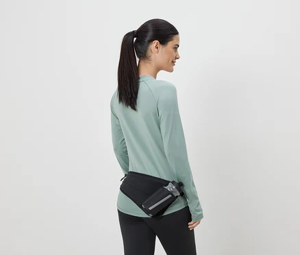 Frau in Sportkleidung mit schwarzer Gürteltasche und Trinkflasche von hinten gesehen.