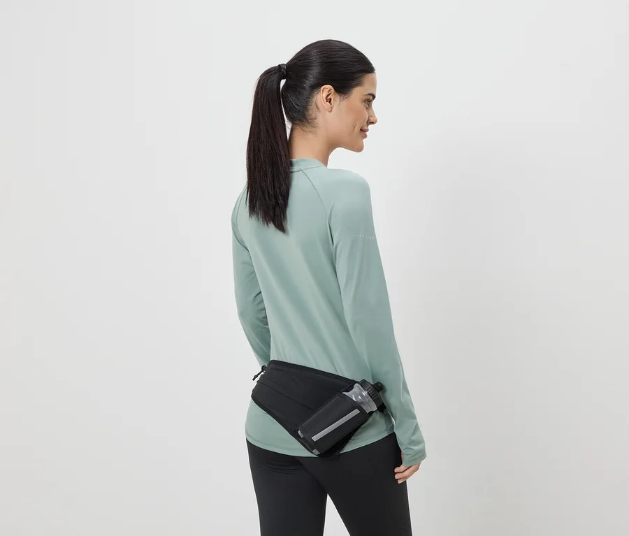 Frau in Sportkleidung mit schwarzer Gürteltasche und Trinkflasche von hinten gesehen.