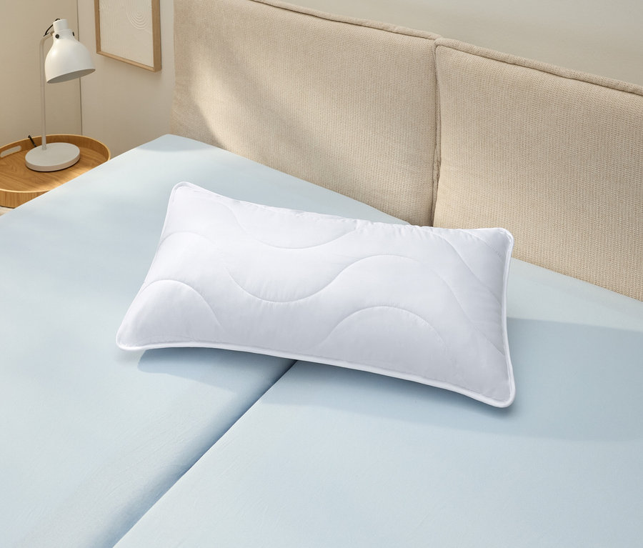 Ein weißes, kochfestes Kopfkissen (ca. 80 x 40) liegt auf einem hellblauen Bettlaken.