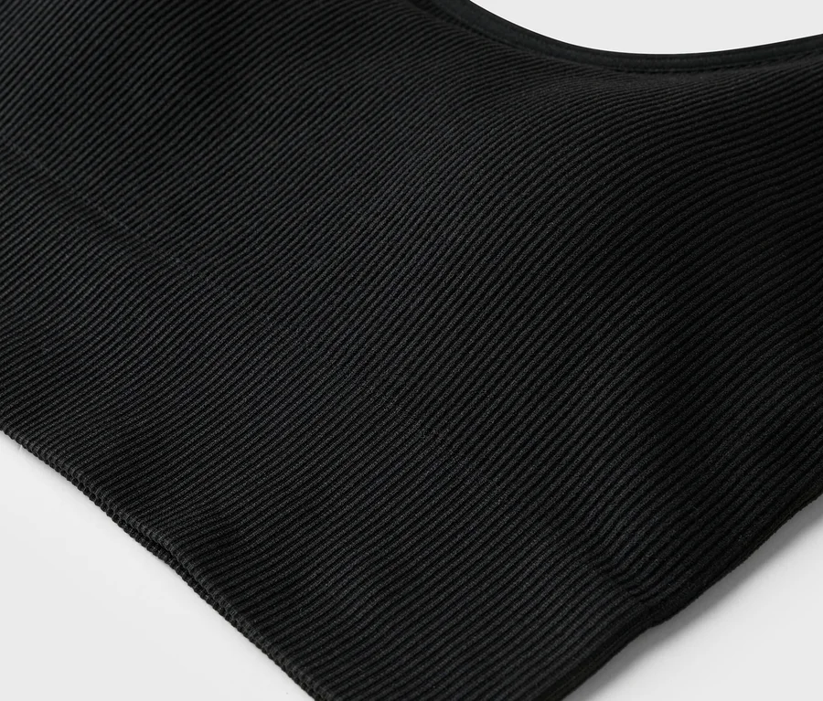 Nahaufnahme eines schwarzen, gerippten Tanktops auf weißem Hintergrund.