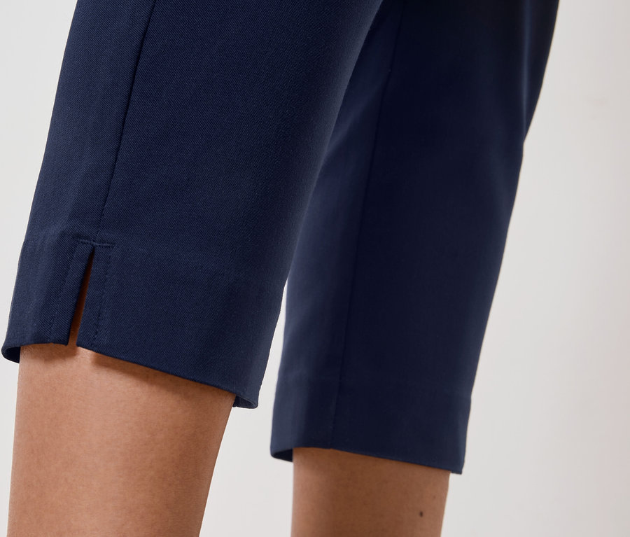 Nahaufnahme der Beine einer Person, die eine marineblaue Hose mit einem Schlitz am Saum trägt.