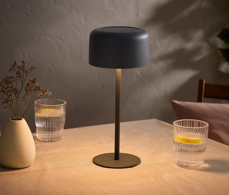 Tisch mit Lampe, Vase mit Blumen und zwei Gläsern Wasser mit Zitrone.