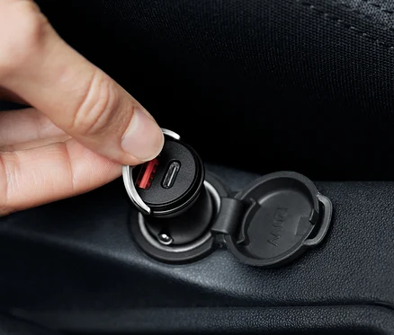 Hand schliesst einen schwarzen USB-C-Autoladegerät an.